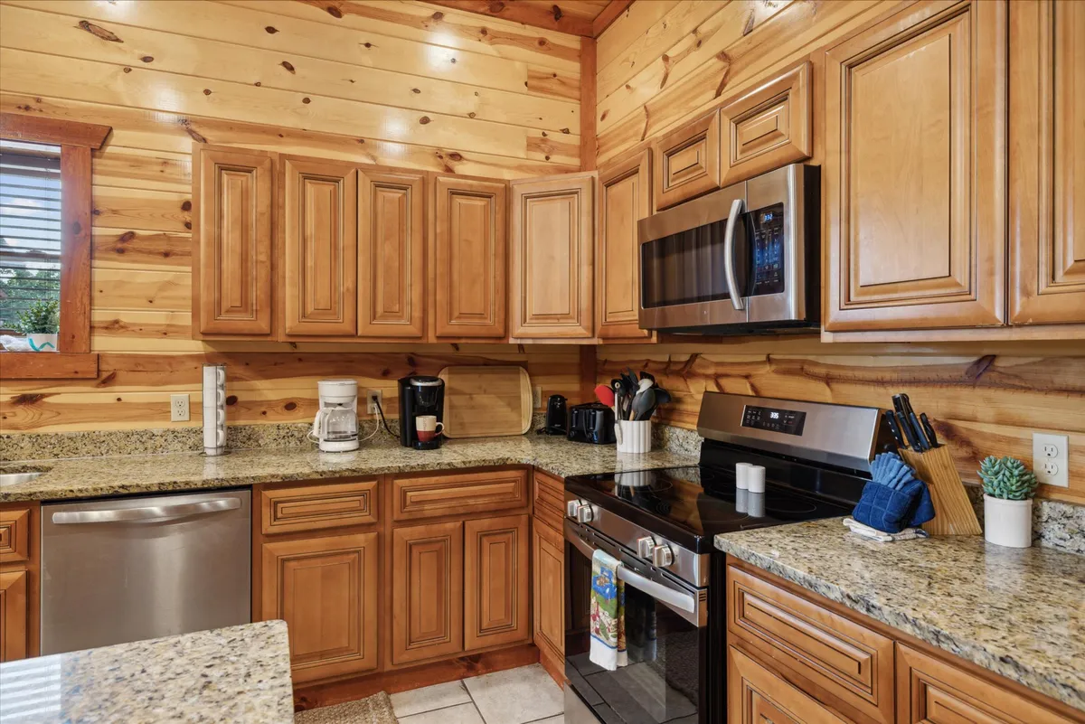 A welcoming kitchen space featuring a granite countertop, warm wooden cabinets, and modern stainless steel appliances. The scene suggests ample room for meal preparation and highlights the inviting, communal atmosphere of the kitchen.