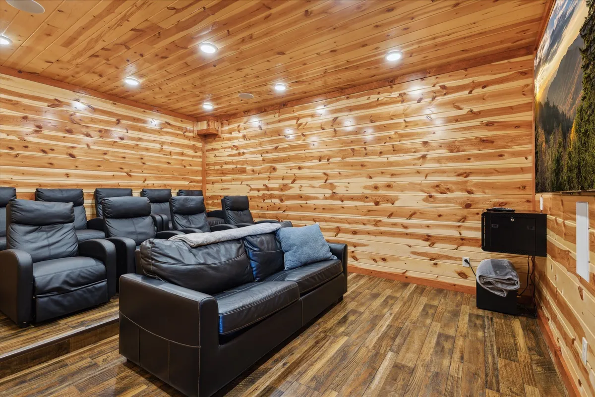 This image displays a dedicated home theater room with comfortable, tiered theater seating facing a large screen. The room is enveloped by rich wood paneling, enhancing the immersive theater experience.