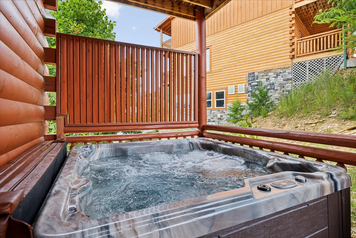 Set against lush greenery, a steaming hot tub sits on a wooden deck with a railing, evoking relaxation after a day of adventure. The setting is tranquil and private, offering sunset or starlit views in a rejuvenating oasis—linking directly to the retreat aspect described in the section.
