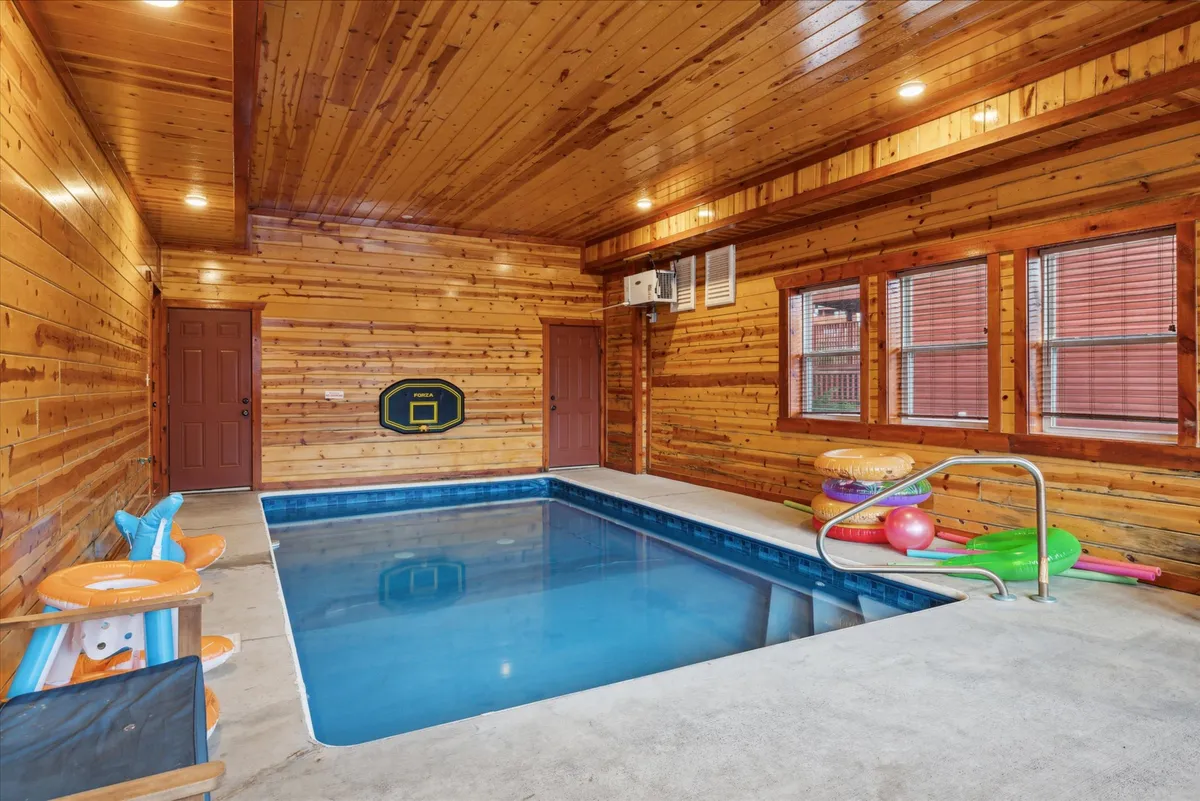 An inviting indoor swimming pool area with wooden walls and colorful pool floats, perfect for groups of all ages. The space is designed for fun and relaxation, offering ample room for swimming, playing pool games, or enjoying quiet moments by the water.